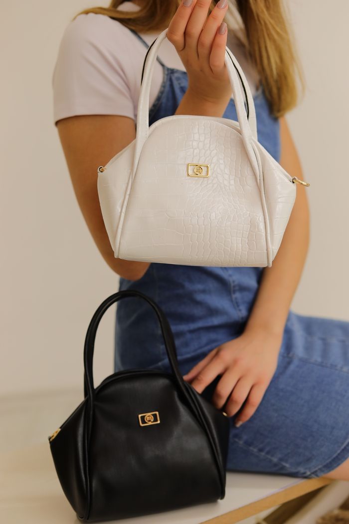 our-mission Elegant black and white handbags displayed in a modern studio setting with a model.