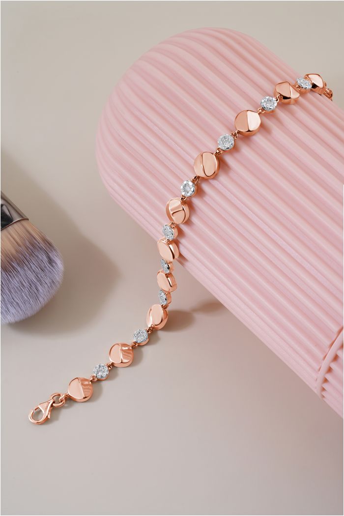 Stylish gold bracelet with diamonds on a pink background showcasing luxury jewelry.
