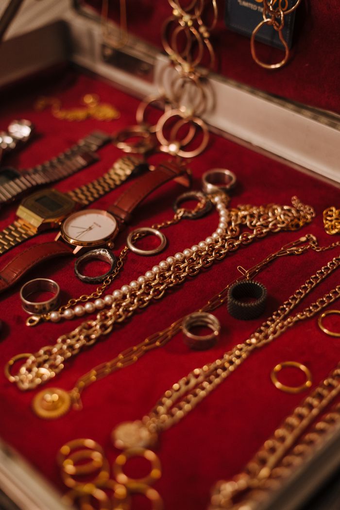 Close-up of various gold and pearl jewelry pieces elegantly arranged in a red velvet box offering a luxurious display.